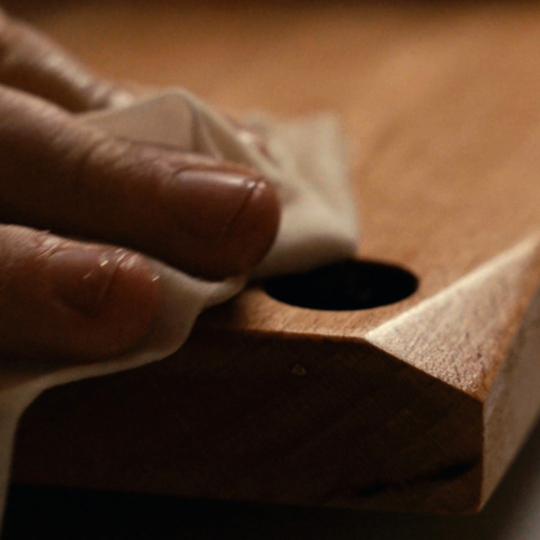 Hands rubbing flaxseed oil into the board